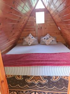 Cama en una cabaña de madera con ventana en Hideaway holt, en Banjār
