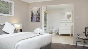 a white bedroom with a bed and a bathroom at Frazer Place - Thoughtful Country Lodge in Daylesford