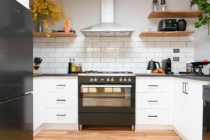 a kitchen with white cabinets and a black oven at Prospect Cottage Ballarat in Ballarat