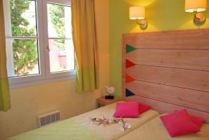 een slaapkamer met een bed met rode kussens bij Lagrange Grand Bleu Vacances – Résidence Le Village des Aloès in Cerbère