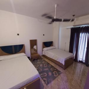 a room with two beds and a ceiling fan at Banana Guest House in Luxor