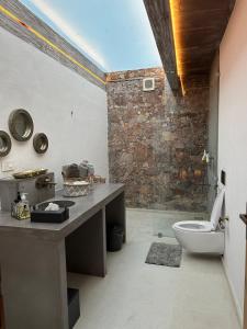 La salle de bains est pourvue de toilettes et d'un mur en pierre. dans l'établissement Kesar Farm House on the Lake, à Udaipur