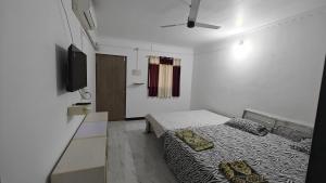 a small room with two beds and a television at Kulswami Cottage Alibag in Alibaug