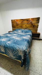a bed with a blue comforter and a wooden headboard at Casa Dahlia Querétaro in Querétaro