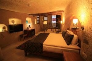 Un dormitorio con una cama y un televisor en una habitación. en Georgios Cave Cappadocia, en Ürgüp