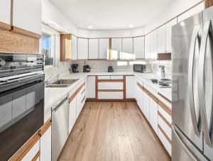 une cuisine avec des armoires blanches et un réfrigérateur en acier inoxydable dans l'établissement Retro Retreat A 60's Time Capsule home, à Grand Junction