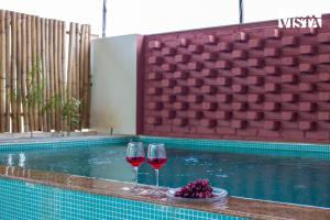 two glasses of red wine next to a swimming pool at StayVista at Ikigai - Pool, AC & Terrace in Udaipur
