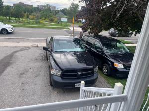 two cars parked in a driveway next to a street at Dar-02 Private Room in Brampton