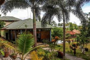 a house with palm trees in front of it at Famoris Cottages in Tetebatu