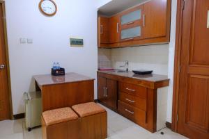 a small kitchen with wooden cabinets and a sink at Scenic 2BR at Grand Setiabudi Apartment By Travelio in Bandung