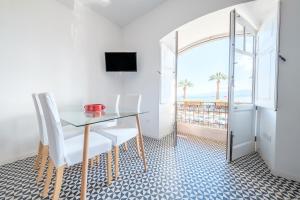 ein Esszimmer mit einem Tisch und Stühlen sowie einem Balkon in der Unterkunft I Mezzanini - Palazzo Bonaccorsi in Milazzo
