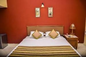 une chambre avec un grand lit aux murs rouges dans l'établissement SAHAY VILLA RESORT, à Durbate 96 autres photos