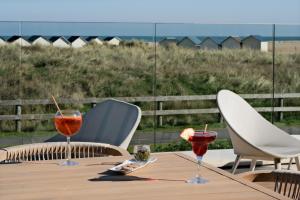 a table with two glasses of wine on a patio at Thalazur Ouistreham - Hôtel & Spa in Ouistreham