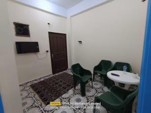 a room with green chairs and a table and a tv at Amoun أمون in Siwa
