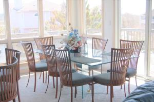 a dining room with a glass table and chairs at M906- Castle De La Mar in Corolla