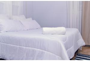 a white bed with white sheets and a towel on it at LYYN Apartments in Chipata