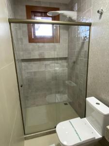 Bangalo Aconchegante - Praia Dulé ES - Suite 1 في غواراباري: حمام مع دش زجاجي ومرحاض