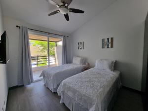 a bedroom with two beds and a ceiling fan at Casa Cardumen - Ciudad Del Mar, in Jaco in Jacó