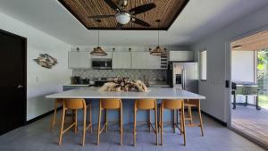 a kitchen with a large white table and chairs at Casa Cardumen - Ciudad Del Mar, in Jaco in Jacó