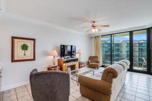 Una sala de estar con un sofá y sillas y un televisor. en Phoenix on the Bay 1412 by Liquid Life, en Orange Beach