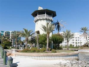 Un faro frente a un edificio con palmeras. en Phoenix on the Bay 1412 by Liquid Life, en Orange Beach