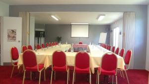 une salle de conférence avec une grande table et des chaises rouges dans l'établissement Logis Cottage Hôtel, à Calais
