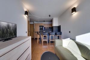 a living room with a couch and a kitchen at Jardins de Val Le charme à la Montagne in Val dʼIsère