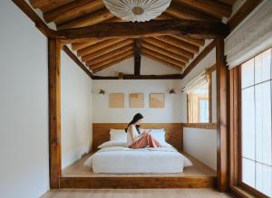 una donna seduta su un letto in una stanza di StayMoire Entire Hanok - Central of Seoul a Seul