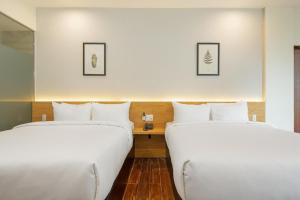 Dos camas en una habitación de hotel con sábanas blancas. en Happy Hotel Here, en Nha Trang