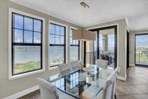 a dining room with a glass table and white chairs at Florencia 708 by Liquid Life in Pensacola
