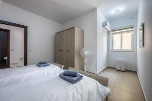 two beds in a white bedroom with blue towels on them at Central Sliema Modern 2 bedroom Apartment Malta in Sliema