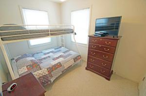 - une chambre avec des lits superposés et une commode avec une télévision dans l'établissement KD2035- The JPC Fisher, à Kill Devil Hills