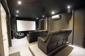 une salle de cinéma avec des fauteuils en cuir et un écran dans l'établissement KD2035- The JPC Fisher, à Kill Devil Hills