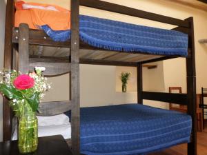a bunk bed with blue sheets and a vase with flowers at OkiDoki Cusco Hostal in Cusco