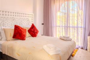 a bedroom with a bed with red pillows and a window at Luxury Villa with Pool, Garden & Gated Security in Marrakech +70 photos