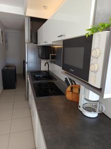 Una cocina con gabinetes blancos y una encimera negra. en tee coco marine, en Saint-François