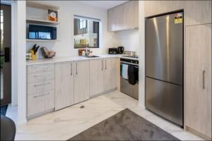 une cuisine avec un réfrigérateur et des armoires en acier inoxydable dans l'établissement Lovely 2 bed 2 bath, à Christchurch 2 autres photos