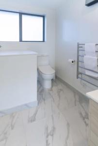 une salle de bain blanche avec toilettes et fenêtre dans l'établissement Lovely 2 bed 2 bath, à Christchurch