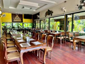 a restaurant with wooden tables and chairs and windows at Kokhaburi Hotel in Ban Na Wiang
