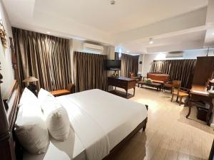 a hotel room with a large bed and a desk at Kokhaburi Hotel in Ban Na Wiang