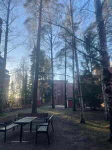 two benches and a table in a park with trees at Free Parking Private ROOM with Balcony, 10mins to Helsinki center in Helsinki