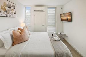 a white bedroom with a large bed and a television at Perch - Centro house F in Seattle