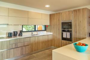 eine Küche mit Holzschränken und einer Obstschale auf der Theke in der Unterkunft Villa Eden Sky in Prazeres in Prazeres