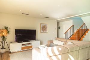 ein Wohnzimmer mit Couch und Flachbildfernseher in der Unterkunft Villa Eden Sky in Prazeres in Prazeres