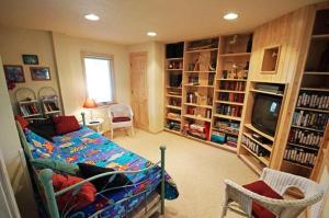 a living room with a bed and a tv and book shelves at WH1020- Crab Quarters in Corolla