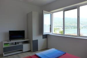 een woonkamer met een tv en 2 ramen bij Villa Nada in Ohrid