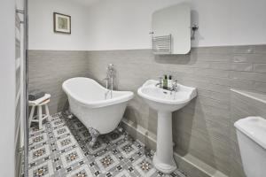 a bathroom with a sink and a tub and a toilet at Host & Stay - Cedar Cottage in Belford