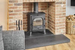 a stove in a living room with a brick wall at Host & Stay - Cedar Cottage in Belford +13 photos