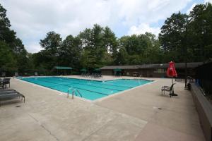 a large swimming pool with chairs and a red umbrella at Blissful Bears Mountain in Brevard