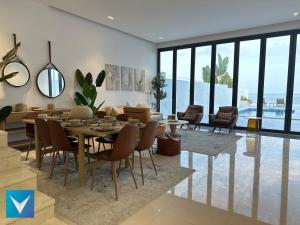 a dining room with a table and chairs and a living room at 3BR Modern Seashore Private Villa with swimming Pool in Fujairah